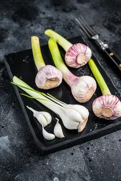 Raw Spring young garlic bulbs and cloves on marble board. Black background. Top Stock Photos