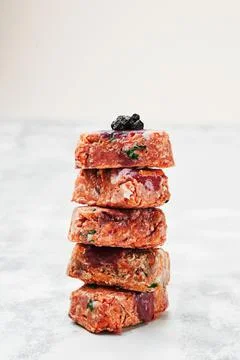 Raw square cutlets on light background. Natural food for dogs. BARF dog diet Stock Photos