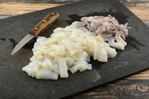 Raw squid tubes and tentacles and knife Stock Photos