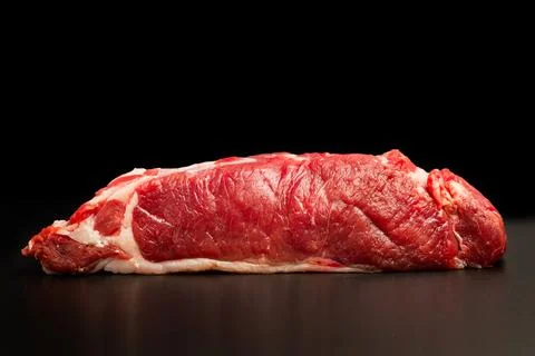 A raw steak on a black table and on a dark background Foto stock