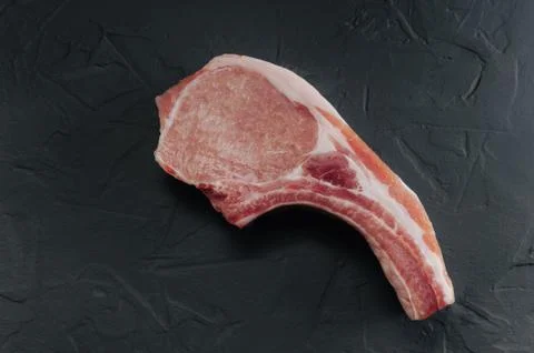 Raw steak on the bone on a gray background, without anything Stock Photos