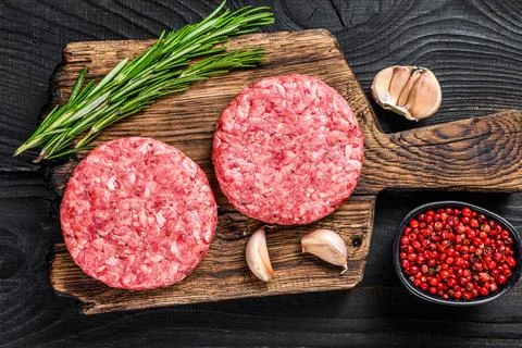 Raw steak cutlets with mince beef meat and rosemary on a wooden cutting board Stock Photos