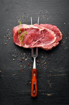 Raw Steak on the fork. At the aged table. Top view. Free space for your text. Stock Photos