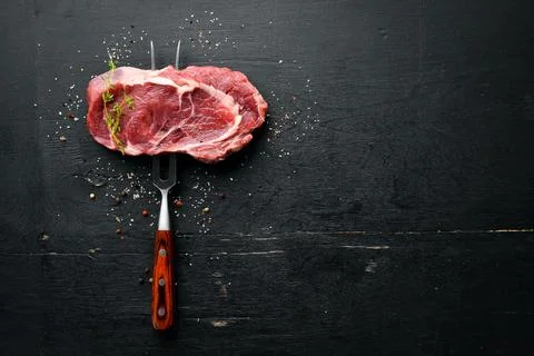 Raw Steak on the fork. At the aged table. Top view. Free space for your text. Stock Photos