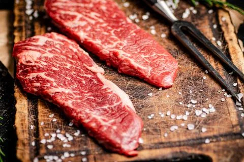 Raw steak with fork on the table. Stock Photos