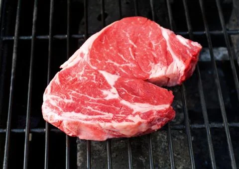 Raw steak on a grill Stock Photos