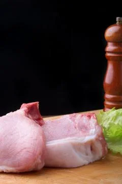 Raw steak on a rustic cutting board with salt, pepper and grinder for spices Stock Photos