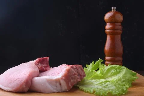 Raw steak on rustic cutting board with salt, pepper and grinder for spices. B Stock Photos
