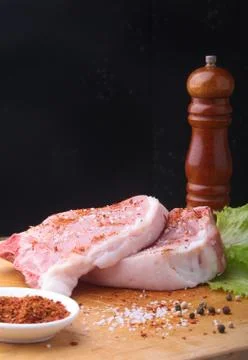 Raw steak on rustic cutting board with salt, pepper and grinder for spices. B Stock Photos