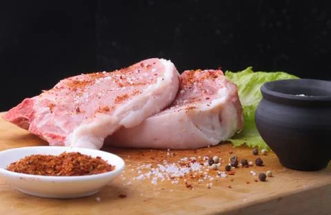 Raw steak on rustic cutting board with salt, pepper and grinder for spices. B Stock Photos
