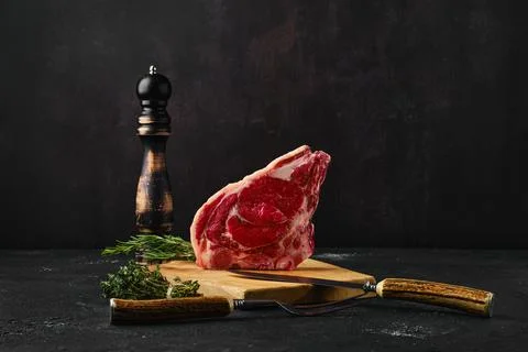 Raw strip steak bone in on dark background Foto stock