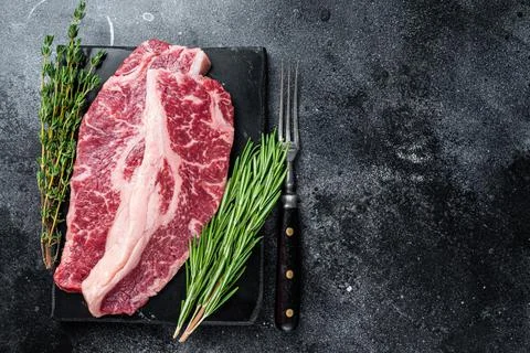 Raw Striploin steak or New York steak beef meat cut. Black background. Top view Stock Photos