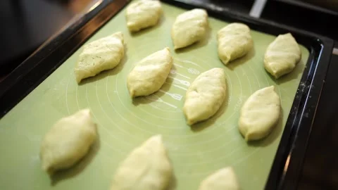 Raw stuffed buns lie on a baking sheet on the table Stock Footage 281301212