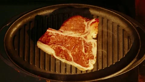Raw t bone steak placed on hot grill pan close up shot food preparation. Stock Footage 346400443