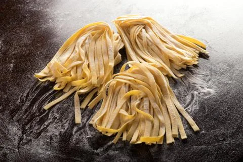 Raw tagliatelle on brown table Stock Photos