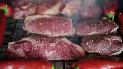 Raw thick beef steaks grilling on outdoor barbecue with red peppers and smo.. Stock Footage 339644032