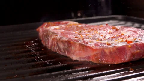 A raw thick delicious meat steak is frying on the hot surface of the grill Stock Footage 129388772