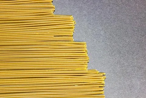 Raw thin spaghetti on a black background lies in the form of steps. Stock Photos
