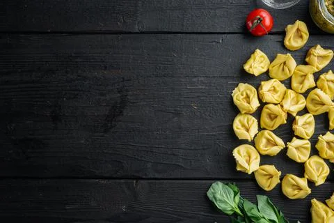 Raw Tortellini with basil and pine pesto, on black wooden table background, t Stock Photos
