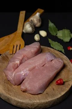 Raw turkey steaks on a black background. Turkey breast fillet on a wooden board. Stock Photos