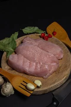 Raw turkey steaks on a black background. Turkey breast fillet on a wooden board. Stock Photos