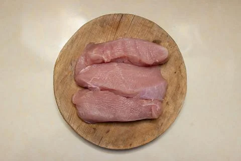 Raw turkey steaks on the kitchen table. Turkey breast fillet on a wooden board. Stock Photos