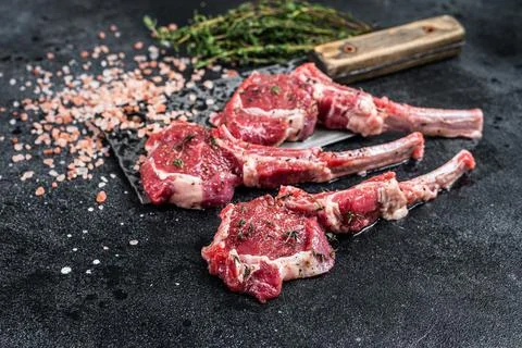 Raw uncooked lamb mutton meat chops steaks on a butcher cleaver. Black Stock Photos