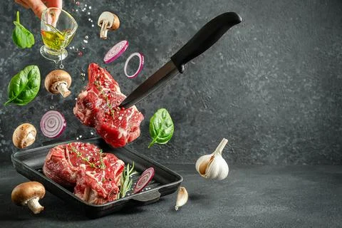 Raw veal bone steak falling on the grill pan with ingredients for cooking o.. Stock Photos