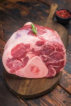 Raw veal shank with bone on wooden board with rosemary and pink pepper rust.. Stockfoto's