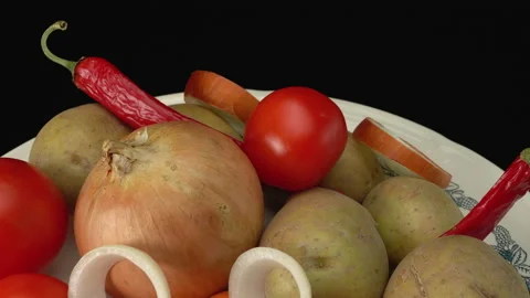 Raw vegetables on a plate. Potatoes, onions, tomatoes, carrots, hot red peppers. Stock-Footage 147974648