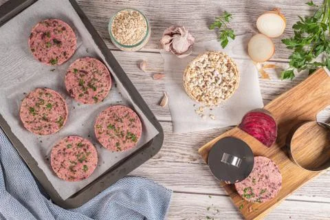 Raw veggie burger with beetroot and white beans with parsley leaves on wood c Stock Photos