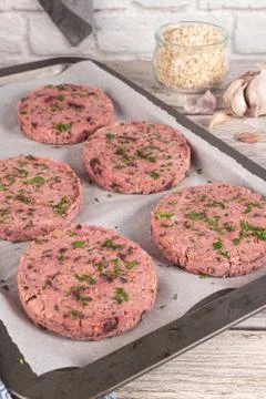 Raw veggie burger with beetroot and white beans with parsley leaves on wood c Stock Photos