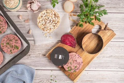 Raw veggie burger with beetroot and white beans with parsley leaves on wood c Stock Photos