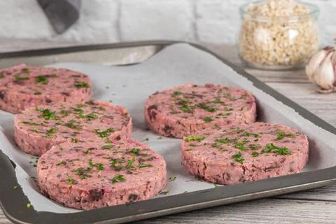 Raw veggie burger with beetroot and white beans with parsley leaves on wood c Stock Photos