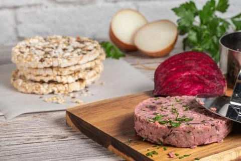 Raw veggie burger with beetroot and white beans with parsley leaves on wood c Stock Photos