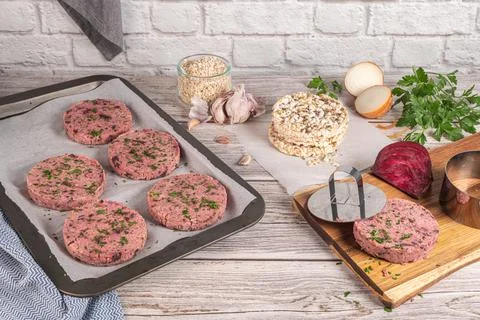 Raw veggie burger with beetroot and white beans with parsley leaves on wood c Stock Photos