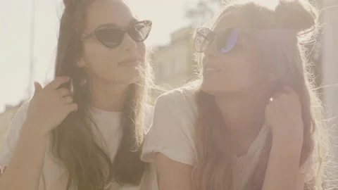 Raw video. Two young beautiful smiling hipster girls in trendy summer clothes Stock Footage 142378258