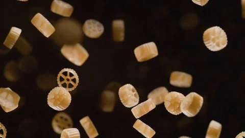 Raw wagon wheels pasta flies after being exploded. Slow Motion. Video stock 76229586