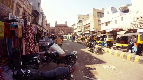 Raw of waiting auto rickshaws indian shops along street big ancient gate behind  Stock Footage 90796420