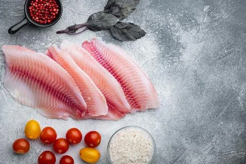 Raw white fish tilapia with basmati rice and cherry tomatoes ingredients, on  Stock Photos