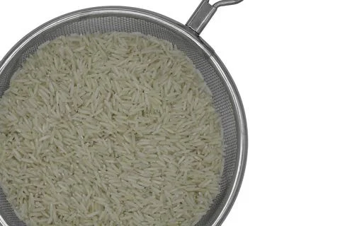 Raw white rice in strainer Stock Photos