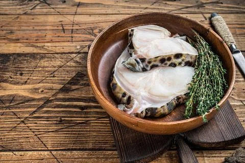 Raw wolffish or wolf fish fillet in a wooden plate. wooden background. Top view Stock Photos