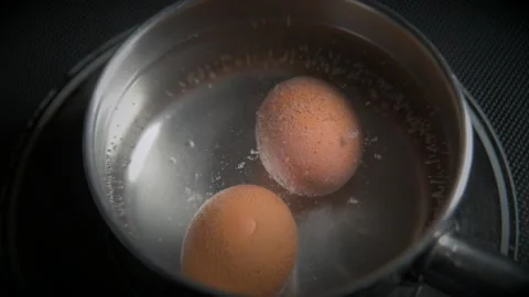 Raw yellow chicken eggs hard boiled in metal pot with boiling water. Healthy nut Stock Footage 168674328