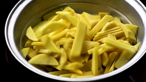 Raw yellow potato wedges falling into a metal colander 4K close-up Видео 330799354