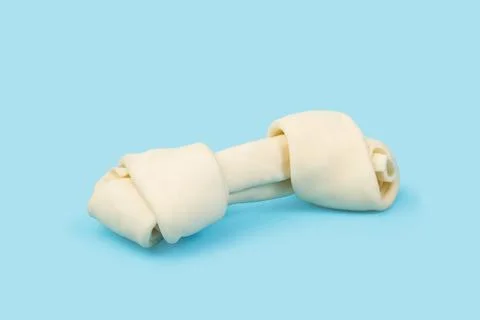 A rawhide bone on a light blue background Stock Photos