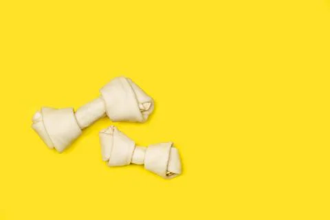 Rawhide bones on a yellow background with copy space Stock Photos