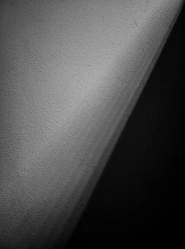 A ray of light divided into gradations passes along the gray concrete wall, d Stock Photos