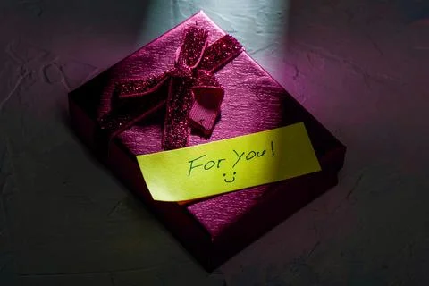 Ray of light on pink gift box with ribbon and note For you. Stock Photos