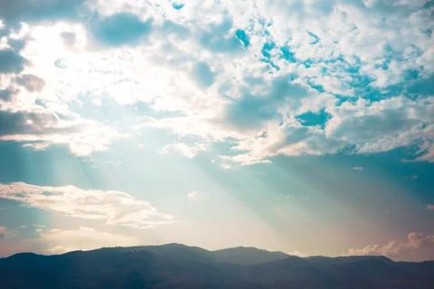 Ray of light sunset behind clouds with silhouette mountains Stock Photos