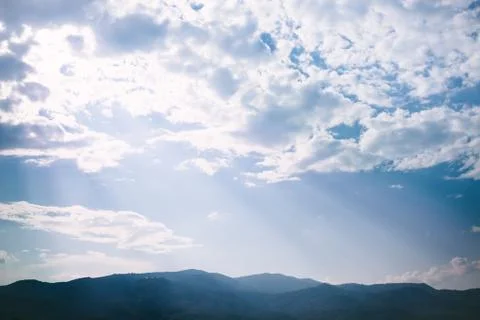 Ray of light sunset behind clouds with silhouette mountains Stock Photos